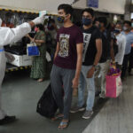 Kiểm tra thân nhiệt tại ga tàu ở Mumbai, Ấn Độ, hôm 19/12. Ảnh: AFP.